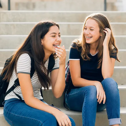 Two teenage friends with braces laughing