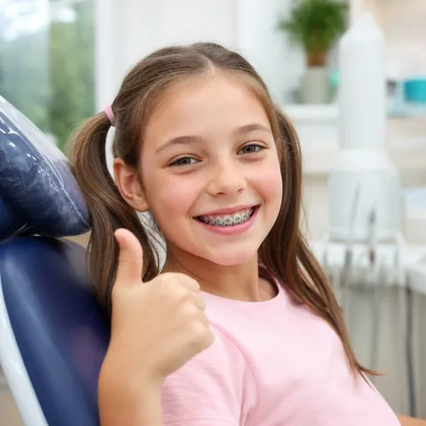 Girl with colorful braces giving a thumbs up